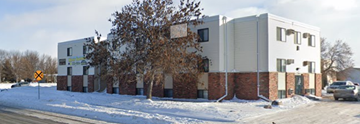 Moorhead apartment for rent - A white and brown building with a yellow sign in front of it.