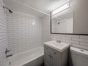 Bridgeport apartment for rent - A white tiled bathroom with a sink, mirror, and bathtub.