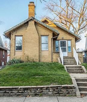 Akron house for rent - A small house with a brick exterior and a stone wall in front.