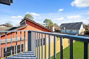 Missouri City house for rent - A balcony with a metal railing overlooks a grassy area and houses.