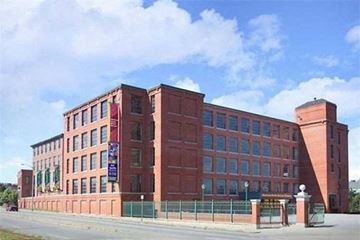 Lowell apartment for rent - A red brick building with a green fence in front.