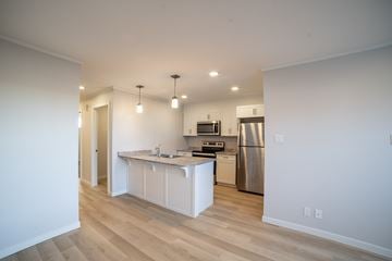 Saskatoon apartment for rent - A kitchen with white cabinets and a wooden floor.