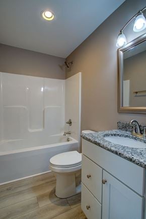 Boone house for rent - A white toilet sits in a bathroom with a marble counter and a mirror above it.