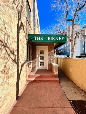 Denver apartment for rent - The Birney building has a green awning and a white door.