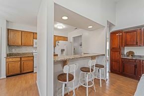 Jacksonville house for rent - A kitchen with white chairs and wooden cabinets.