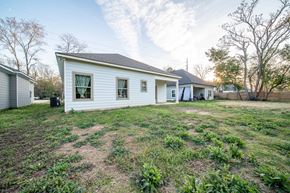 Phenix City house for rent - A white house with a grey roof is surrounded by a grassy area.