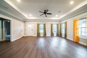 Phenix City house for rent - A spacious room with wooden floors and a ceiling fan.