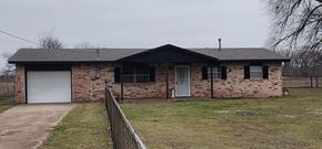 Harrah house for rent - A brick house with a white garage door and a black roof.