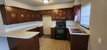 Harrah house for rent - A kitchen with brown cabinets and a black stove top oven.