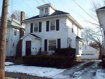 Lansing house for rent - A white house with a black roof and a chimney.
