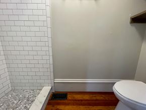 Louisville apartment for rent - A white toilet sits next to a white tiled wall.