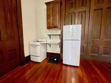 Louisville apartment for rent - A white refrigerator stands in a kitchen with wooden floors and cabinets.