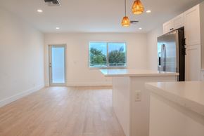 Delray Beach apartment for rent - A kitchen with a refrigerator, countertop, and a window with a view of trees.