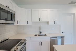 Delray Beach apartment for rent - A kitchen with white cabinets and a black stove top.