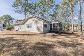 Midway Park house for rent - A house with a porch and a fence is surrounded by trees.