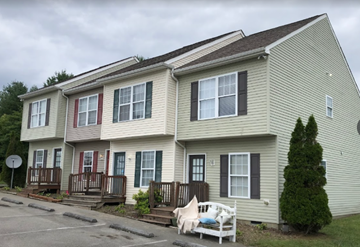 Wise apartment for rent - A two-story house with a red door and a white chair on the porch.