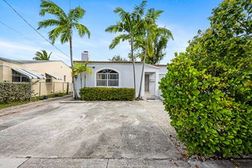Miami triplex for rent - A house with a driveway and a palm tree in front.