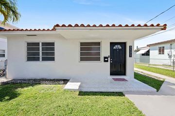 Miami triplex for rent - A small white house with a black door and windows.