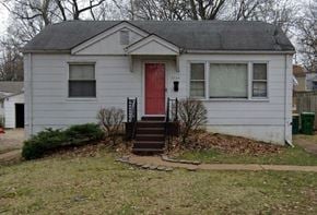 St Louis house for rent - A small house with a red door and a window with white curtains.