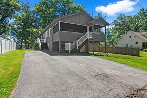 Cedar Lake house for rent - A grey house with a porch and a driveway in front.