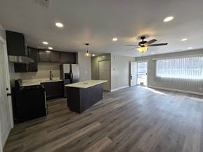 Gary house for rent - A spacious kitchen and living room with dark wood flooring and white walls.
