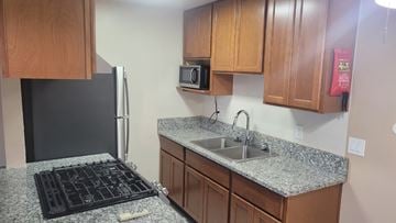 Stockton apartment for rent - A kitchen with a black fridge, granite countertop, and wooden cabinets.