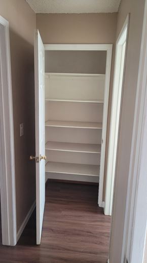 Stockton apartment for rent - A white door is open to a hallway with shelves.