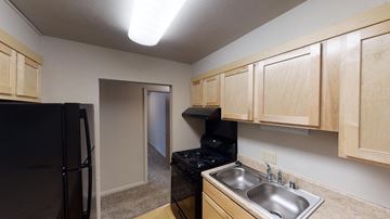 Sun Prairie apartment for rent - A kitchen with wooden cabinets and a black fridge.