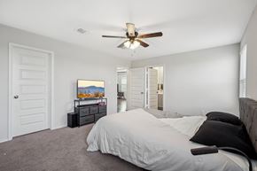 Von Ormy house for rent - A bedroom with a large bed and a ceiling fan.