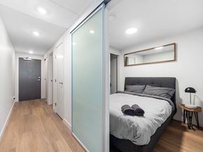 Calgary apartment for rent - A bedroom with a bed, a mirror, and a lamp.