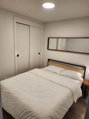 Calgary apartment for rent - A bed with white bedding sits in a room with a mirror and a door.