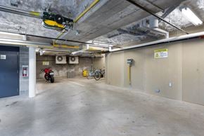 Vancouver apartment for rent - A motorcycle is parked in a concrete garage with a yellow caution sign on the wall.
