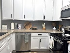 Glendale apartment for rent - A kitchen with white cabinets and black appliances.