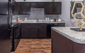 Fort Worth apartment for rent - A kitchen with dark wood cabinets and a black refrigerator.