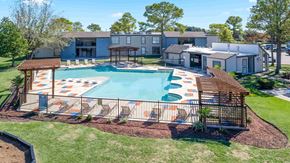 Houston apartment for rent - A swimming pool with a wooden deck and a building in the background.