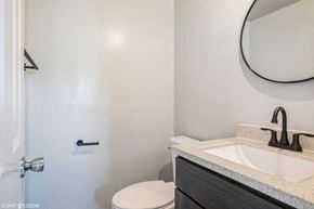 Gary house for rent - A bathroom with a white toilet and a sink with a black faucet.