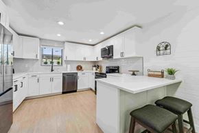 Phoenix apartment for rent - A kitchen with white cabinets and a large island with two stools.