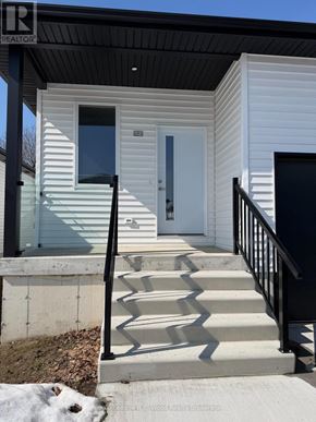 Aylmer townhouse for rent - A small white house with a black railing and steps leading to a white door.