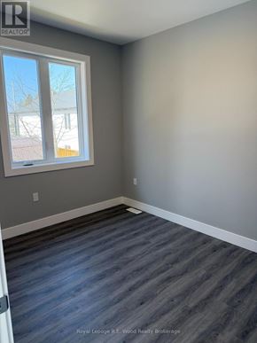 Aylmer townhouse for rent - A room with a grey wall and a window with a view of a tree and a building outside.