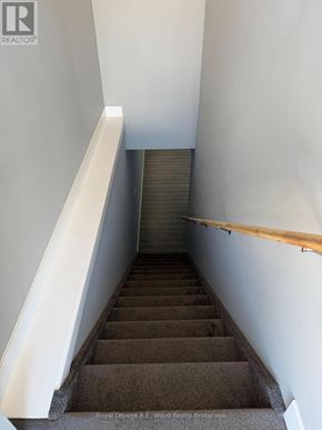 Aylmer townhouse for rent - A staircase with a wooden handrail and a white wall on the side.