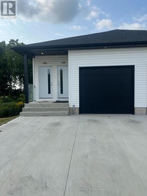 Aylmer townhouse for rent - A white house with a black garage door and a realtor logo on the top left.