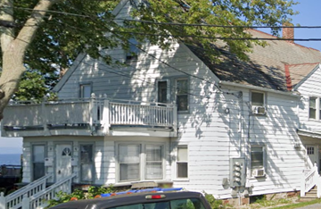 Burlington apartment for rent - A white house with a balcony and a car parked in front.