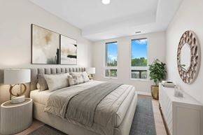 Napanee apartment for rent - A bedroom with a large bed, a lamp, and a mirror on the wall.