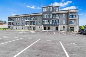 Napanee apartment for rent - A large apartment complex with a parking lot in front.