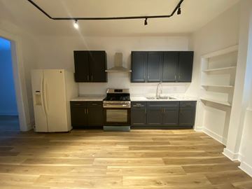 Louisville apartment for rent - A kitchen with black cabinets and a white fridge.