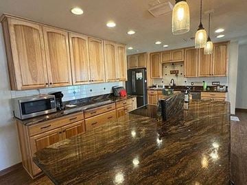 Chandler house for rent - A kitchen with wooden cabinets and a granite countertop.