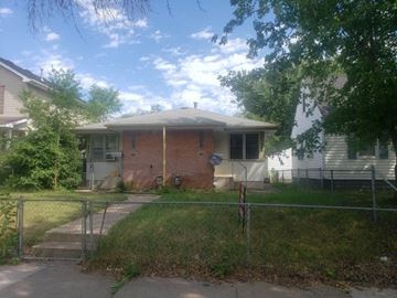 South Saint Paul apartment for rent - A house with a red brick chimney and a grey roof is surrounded by a fence and greenery.