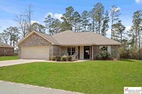 Purvis house for rent - A house with a garage is surrounded by a grassy lawn.