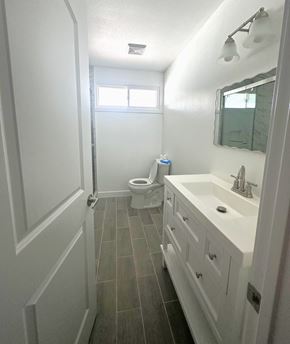 Ontario house for rent - A white bathroom with a toilet, sink, and mirror.