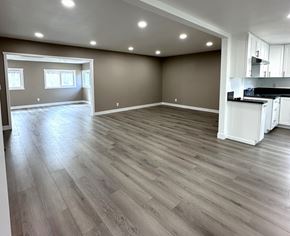 Ontario house for rent - A spacious room with wooden flooring and a kitchen area to the right.